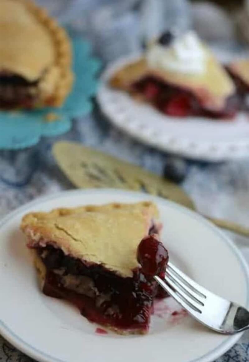 Slice of Berry Delicious Triple Berry Pie with cherry on a fork