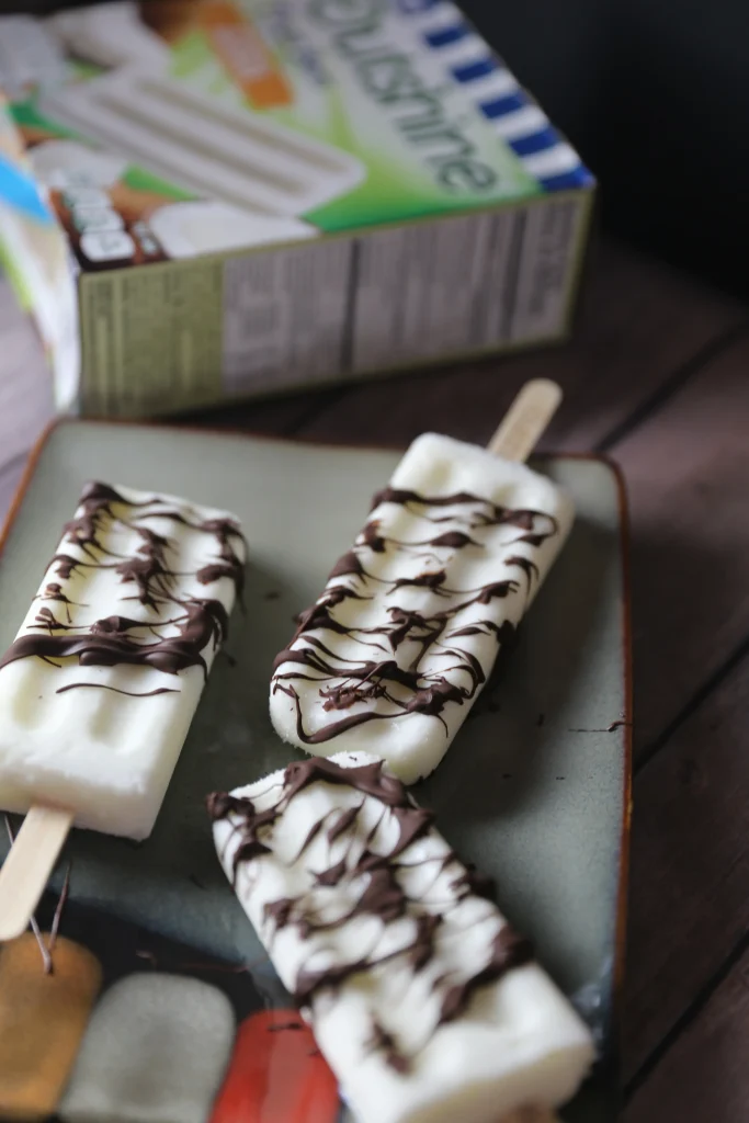 Easy Summer Recipes Roundup: Beat The Heat 16 Simple Recipes 11 outshine bars on a plate with chocolate drizzled on top of them.