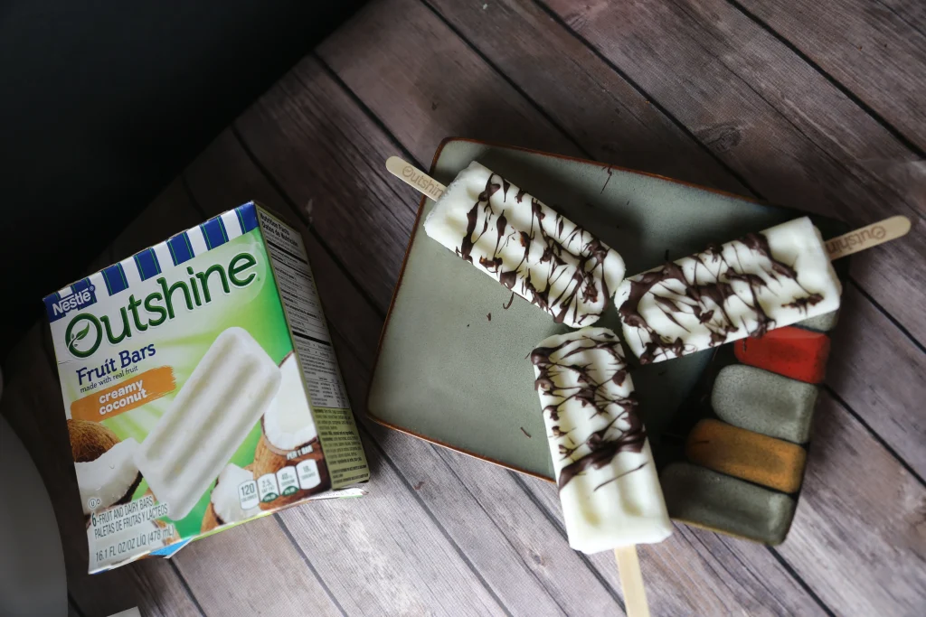 Creamy Coconut Fruit Bars with Chocolate Drizzle 13 three coconut oushine bars laying on plate with chocolate drizzle on them.