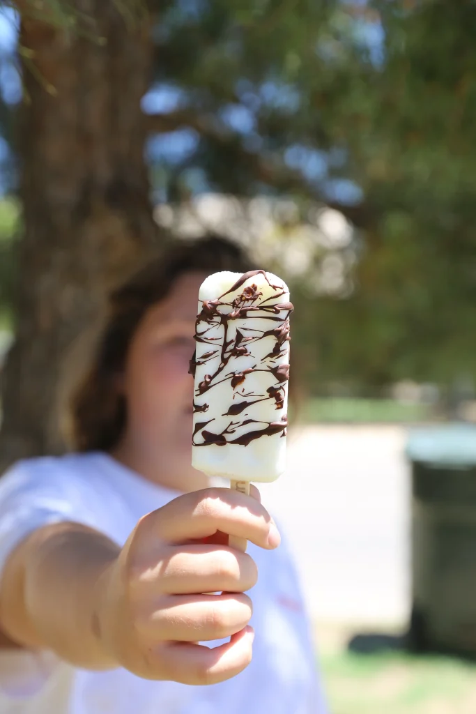 Creamy Coconut Fruit Bars with Chocolate Drizzle 11 jenn brockman's daughter vayda worden holding outshine bar with chocolate on it