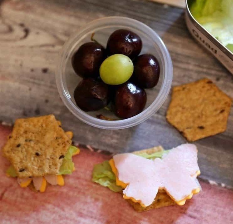 flower made out of cherries and a grape with butterfly cracker sandwich 