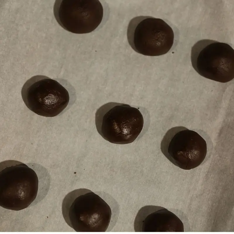 5-Ingredient Fudgy Brownie Crinkle Cookies 12 brownie cookie dough rolled into balls on parchment paper