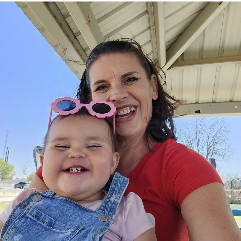 3 Secrets to How I Mentally Prepared to Quit Smoking 11 Jenn Brockman owner of Half Baked Media smiling with granddaughter on her lap wearing pink sunglasses on her head.